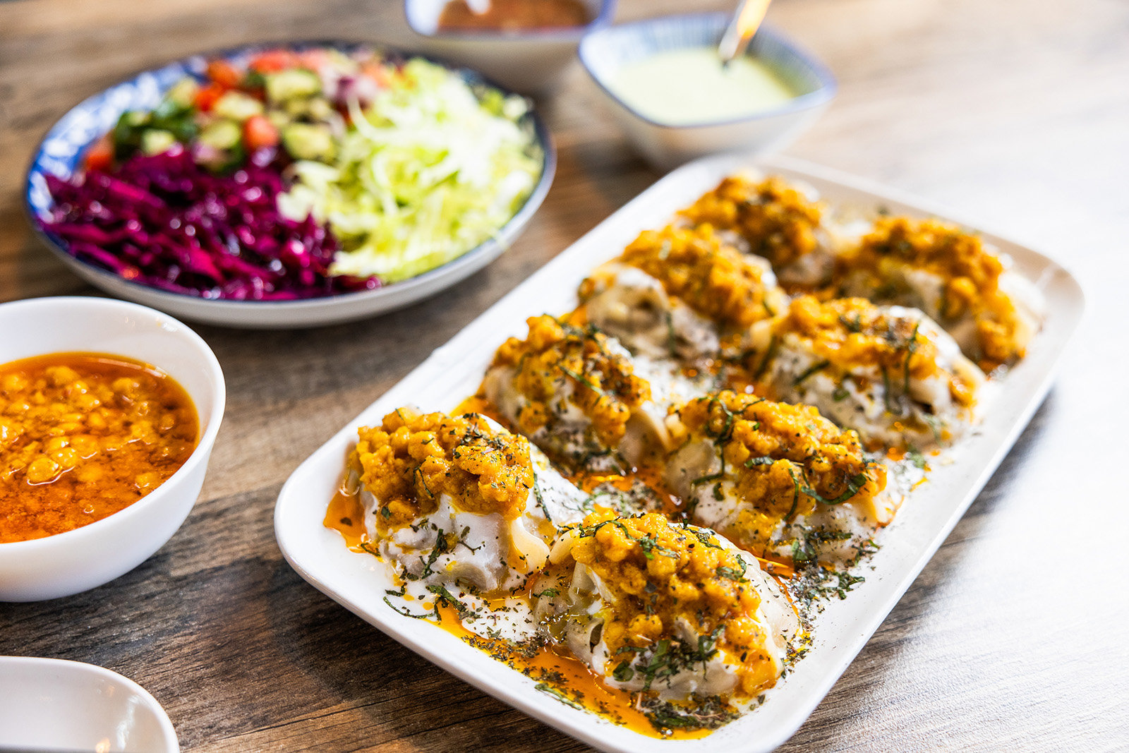 Afghan Mantu — steamed dumplings filled with seasoned beef, topped with yogurt and lentil sauce
